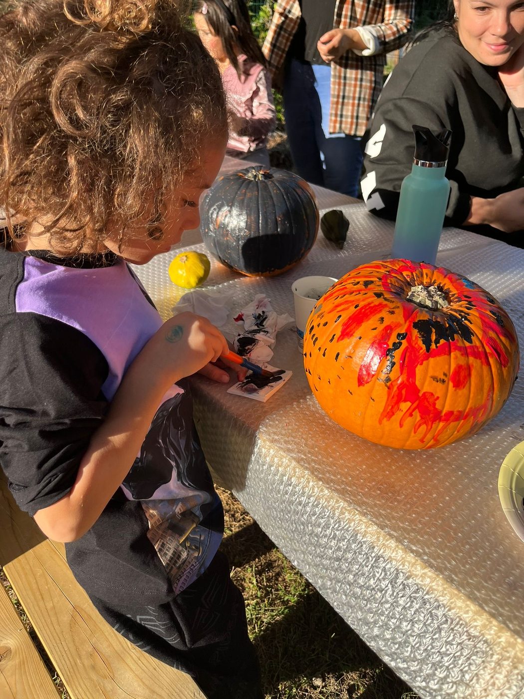 Bambino dipinge una zucca arancione con i colori durante il laboratorio creativo