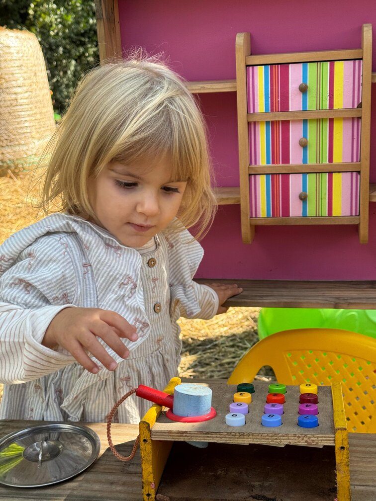 Bambina gioca con un banco da lavoro in legno colorato nella zona dedicata ai più piccoli